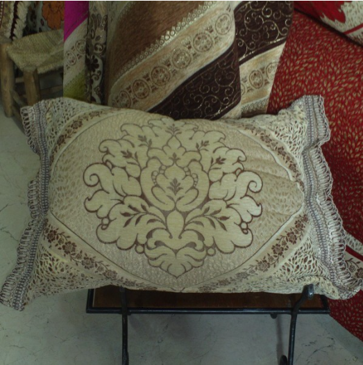 Housse de coussin marocaine ornée de motifs floraux bordée d'un liseré.